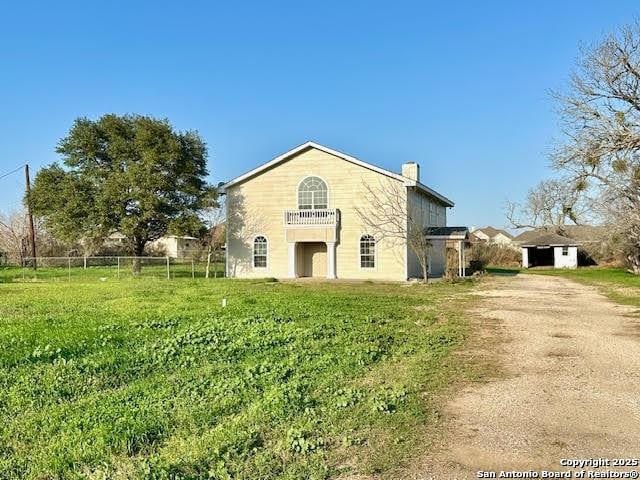 714 N Carroll, Poth, TX 78147 - view of front facade with dirt driveway, a chimney, a balcony, and fence