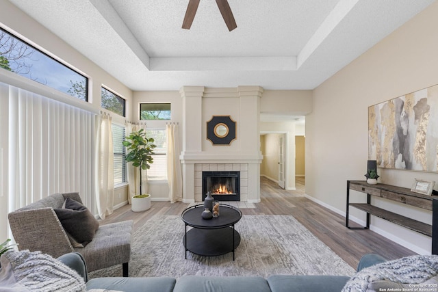 11302 Cedar Park, San Antonio, TX 78249 - living room featuring a ceiling fan, a tray ceiling, wood finished floors, and a tile fireplace