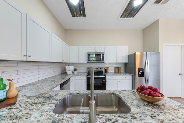 11302 Cedar Park, San Antonio, TX 78249 - kitchen featuring appliances with stainless steel finishes, white cabinetry, light stone countertops, tasteful backsplash, and a textured ceiling
