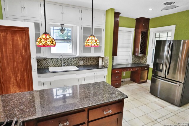 1919 W Magnolia Ave, San Antonio, TX 78201 - kitchen with stainless steel fridge with ice dispenser, a sink, backsplash, light tile patterned floors, and dark stone countertops