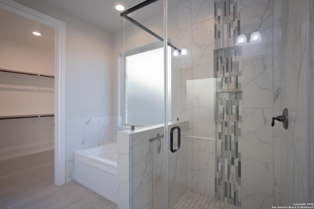 4862 Blue Jasmin, San Antonio, TX 78245 - bathroom featuring a stall shower, a bath, a spacious closet, recessed lighting, and wood finished floors
