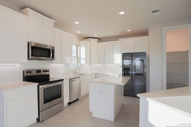 4862 Blue Jasmin, San Antonio, TX 78245 - kitchen with appliances with stainless steel finishes, decorative backsplash, white cabinetry, a kitchen island, and recessed lighting