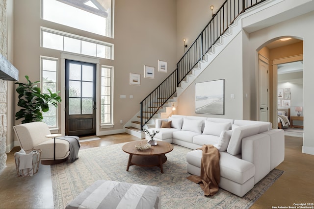 2191 Grandview Frst, Canyon Lake, TX 78133 - living room with a towering ceiling, arched walkways, stairway, baseboards, and concrete flooring