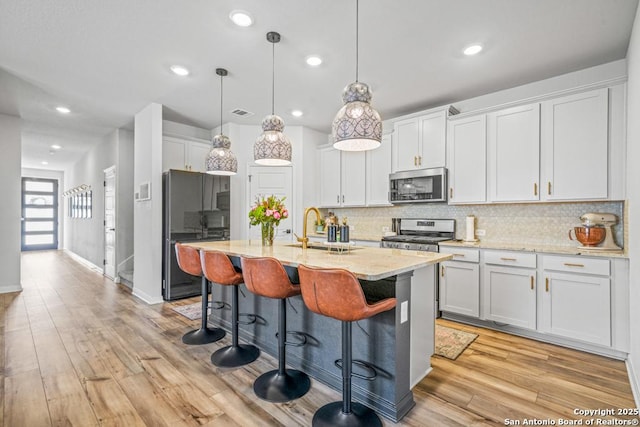 25826 Marigold Oaks, Boerne, TX 78006 - kitchen with stainless steel appliances, a sink, decorative backsplash, a breakfast bar area, and light stone counters