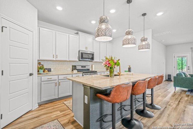 25826 Marigold Oaks, Boerne, TX 78006 - kitchen featuring appliances with stainless steel finishes, a sink, a center island with sink, backsplash, and a breakfast bar area