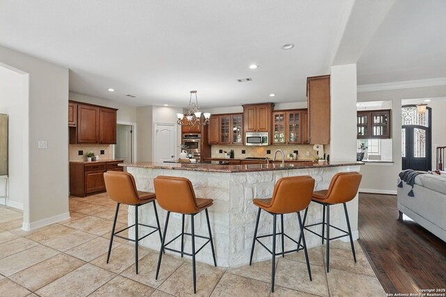 51 Stonewall Bnd, San Antonio, TX 78256 - kitchen with stainless steel microwave, a breakfast bar area, brown cabinets, tasteful backsplash, and recessed lighting