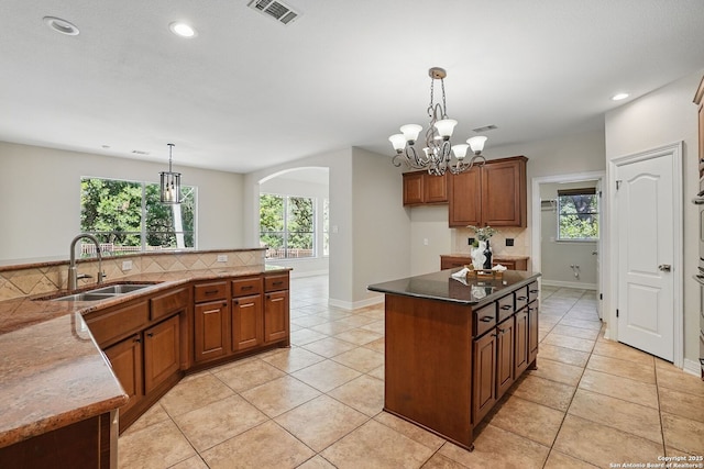 51 Stonewall Bnd, San Antonio, TX 78256 - kitchen featuring a sink, arched walkways, brown cabinetry, a kitchen island, and recessed lighting