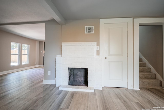 312 Avondale, San Antonio, TX 78223 - unfurnished living room featuring wood finished floors, stairway, beamed ceiling, a fireplace, and baseboards