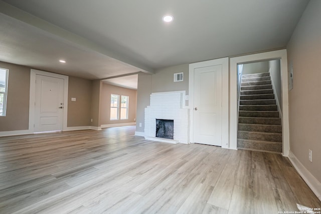 312 Avondale, San Antonio, TX 78223 - unfurnished living room with light wood-style flooring, stairway, baseboards, a brick fireplace, and recessed lighting