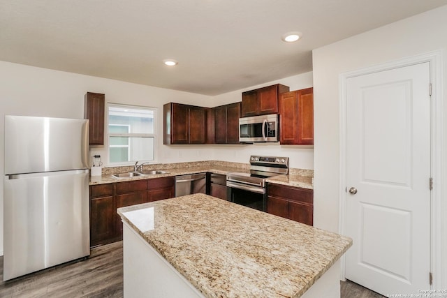 237 Corliss, San Antonio, TX 78220 - kitchen with stainless steel appliances, a sink, wood finished floors, a kitchen island, and light stone countertops