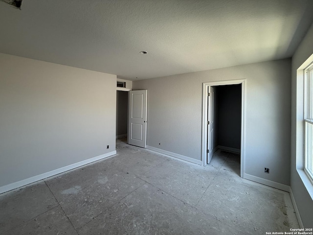 14724 Sycamore Xing, San Antonio, TX 78252 - unfurnished bedroom featuring baseboards, multiple windows, a spacious closet, and a textured ceiling