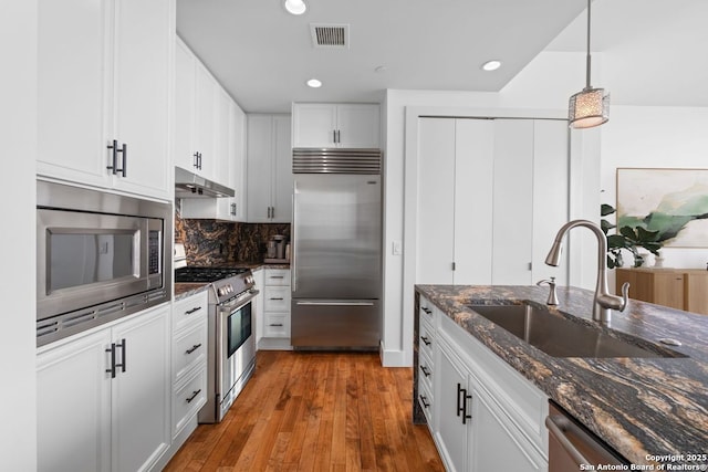 610 E Market St Unit 3110, San Antonio, TX 78205 - kitchen featuring built in appliances, a sink, under cabinet range hood, wood finished floors, and white cabinets