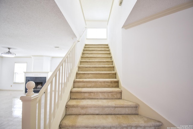 15850 Marisa Pl, San Antonio, TX 78247 - stairs featuring a textured ceiling, a fireplace, and ornamental molding
