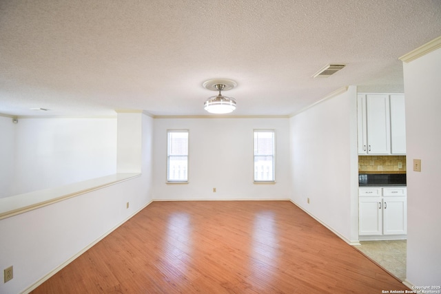 15850 Marisa Pl, San Antonio, TX 78247 - empty room featuring light wood-type flooring, a textured ceiling, crown molding, and baseboards