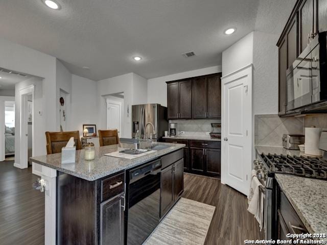 4047 Legend Mdws, New Braunfels, TX 78130 - kitchen with appliances with stainless steel finishes, dark brown cabinetry, dark wood-style flooring, backsplash, and light stone counters