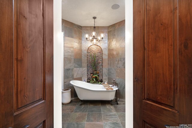2219 Clubs Dr, Boerne, TX 78006 - bathroom featuring tile walls, a freestanding tub, and a chandelier