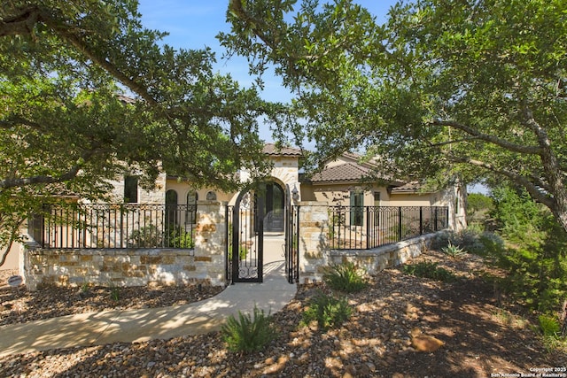 2219 Clubs Dr, Boerne, TX 78006 - mediterranean / spanish-style house featuring a fenced front yard, stucco siding, stone siding, and a gate
