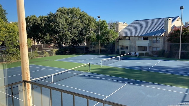 view of tennis court with community basketball court and fence