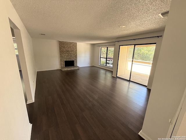 unfurnished living room with a textured ceiling, dark wood-style flooring, a fireplace, and baseboards