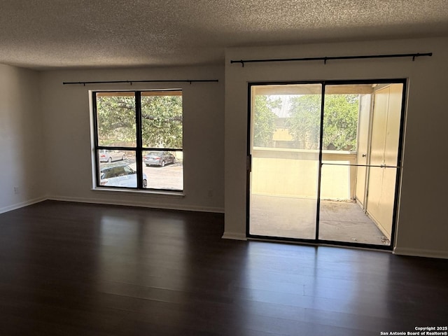 unfurnished room featuring a textured ceiling, dark wood-style flooring, and baseboards