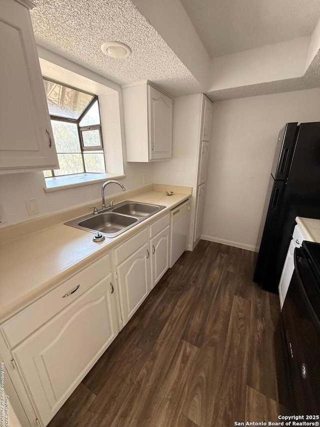 kitchen with white dishwasher, a sink, dark wood-style floors, stove, and white cabinetry