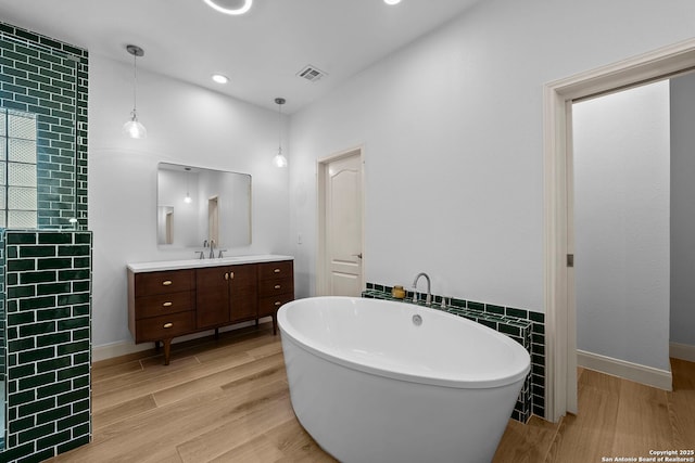 9403 Gardenia Bnd, San Antonio, TX 78266 - full bathroom with a soaking tub, vanity, wood finished floors, baseboards, and recessed lighting