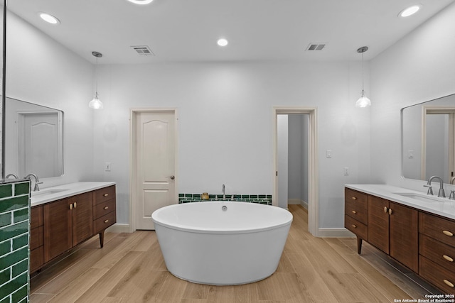 9403 Gardenia Bnd, San Antonio, TX 78266 - full bath featuring wood finished floors, two vanities, a soaking tub, baseboards, and recessed lighting