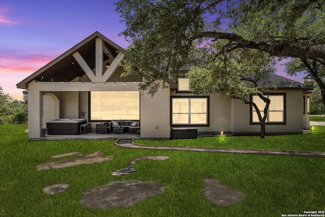 2319 Cascada, Spring Branch, TX 78070 - back of property at dusk featuring stucco siding, a lawn, outdoor lounge area, and a patio area
