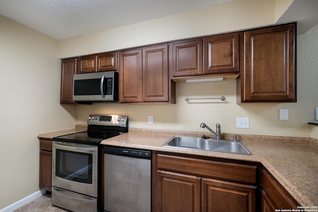 3243 Nacogdoches Rd Unit 501, San Antonio, TX 78217 - kitchen featuring appliances with stainless steel finishes, a sink, a textured ceiling, light countertops, and baseboards