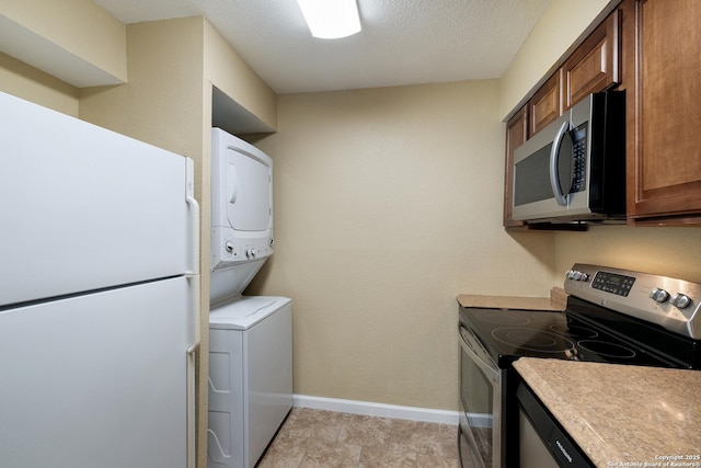 3243 Nacogdoches Rd Unit 501, San Antonio, TX 78217 - laundry room with stacked washer and clothes dryer, baseboards, and a textured ceiling