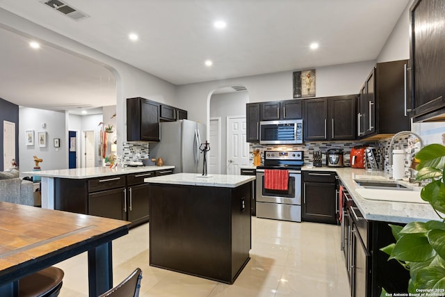 5527 Arcadia Park, San Antonio, TX 78247 - kitchen with stainless steel appliances, arched walkways, a sink, decorative backsplash, and light stone countertops