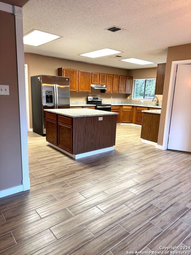 4231 Misty Glade, San Antonio, TX 78247 - kitchen with stainless steel appliances, under cabinet range hood, wood finish floors, a center island, and light countertops