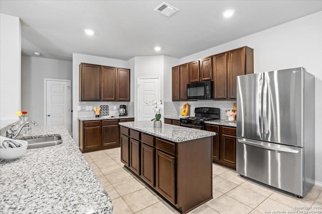 140 Whitetail Pass, San Antonio, TX 78253 - kitchen with black appliances, a kitchen island, decorative backsplash, a sink, and light stone counters