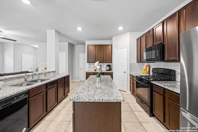 140 Whitetail Pass, San Antonio, TX 78253 - kitchen with black appliances, a sink, a kitchen island, decorative backsplash, and light stone countertops