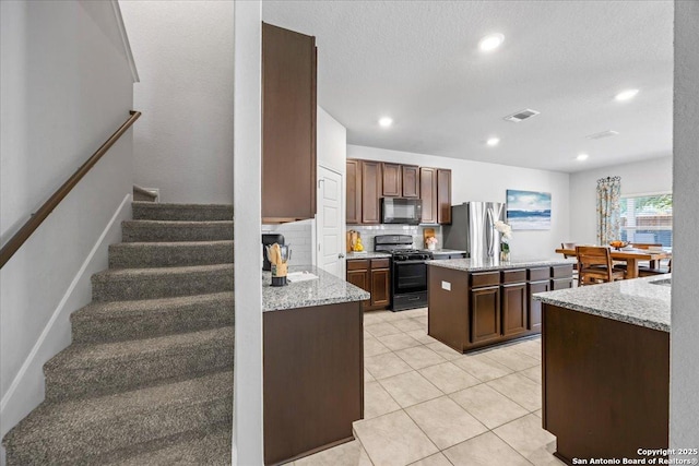 140 Whitetail Pass, San Antonio, TX 78253 - kitchen with black appliances, a center island, backsplash, light stone countertops, and light tile patterned floors