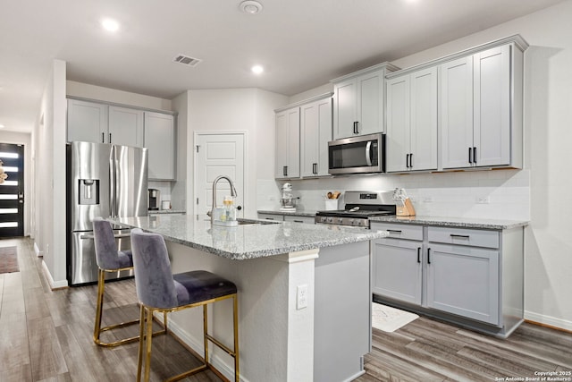 10227 Amaryllis, Boerne, TX 78006 - kitchen featuring appliances with stainless steel finishes, wood finished floors, backsplash, light stone counters, and recessed lighting