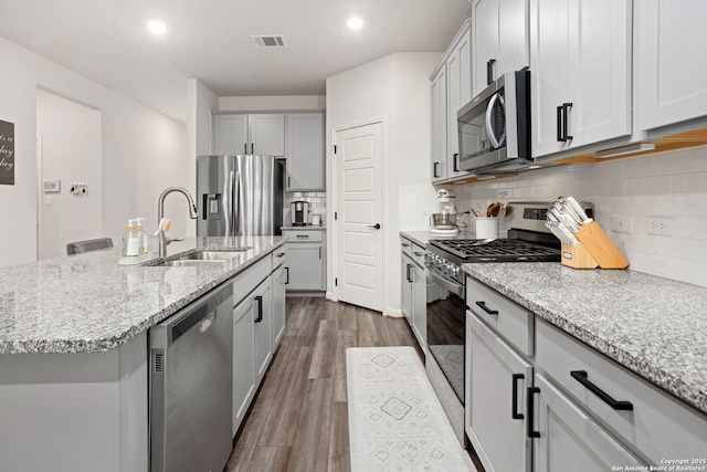 10227 Amaryllis, Boerne, TX 78006 - kitchen with stainless steel appliances, a sink, dark wood-type flooring, tasteful backsplash, and light stone countertops