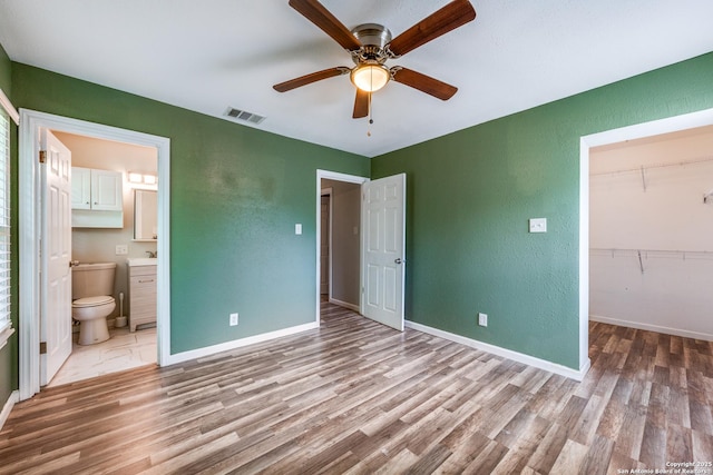 466 Shannon Lee, San Antonio, TX 78216 - unfurnished bedroom featuring wood finished floors, a textured wall, a closet, ensuite bath, and a walk in closet