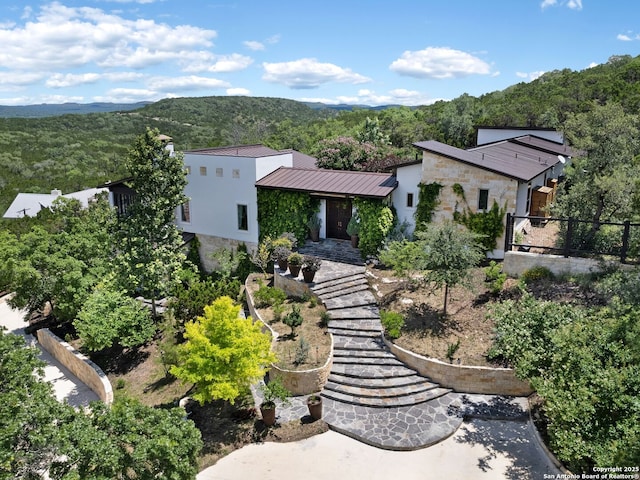 21214 W Tejas Trl, San Antonio, TX 78257 - view of front of property with stone siding, fence, a forest view, metal roof, and a standing seam roof
