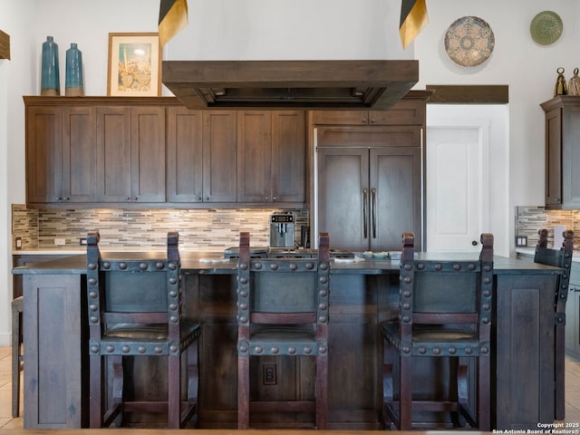 21214 W Tejas Trl, San Antonio, TX 78257 - kitchen with island range hood, tasteful backsplash, a kitchen bar, dark countertops, and paneled refrigerator