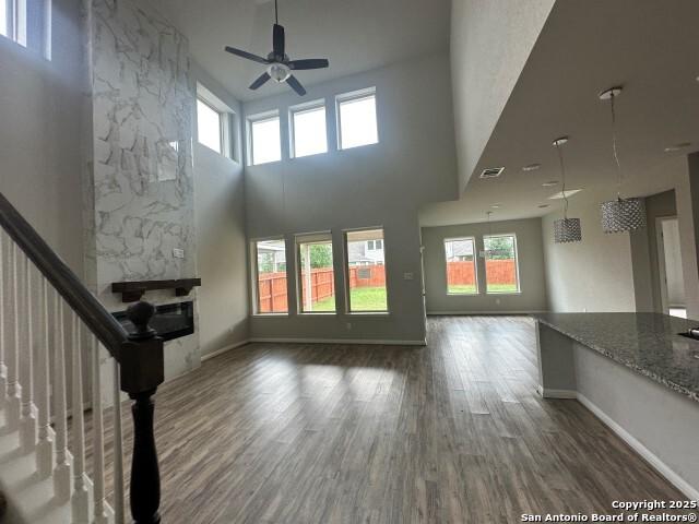 9536 Garrison Way, San Antonio, TX 78254 - unfurnished living room featuring a ceiling fan, wood finished floors, baseboards, a fireplace, and a towering ceiling