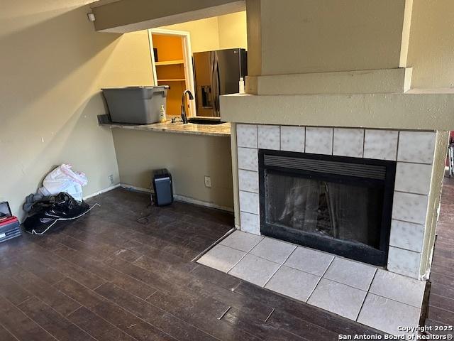 9151 Tree Vlg, San Antonio, TX 78250 - unfurnished living room with wood finished floors and a tile fireplace