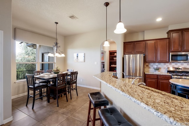 25838 Echo Mtn, San Antonio, TX 78260 - kitchen with appliances with stainless steel finishes, baseboards, backsplash, arched walkways, and pendant lighting