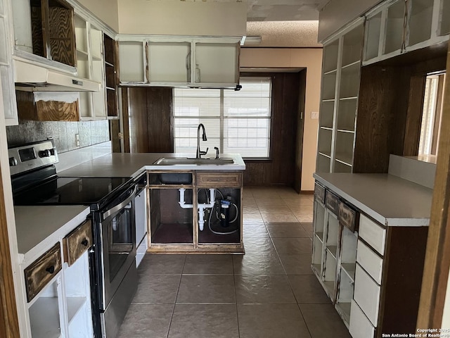 608 Leona St, Cotulla, TX 78014 - kitchen featuring stainless steel range with electric cooktop, a sink, dark tile patterned floors, under cabinet range hood, and light countertops