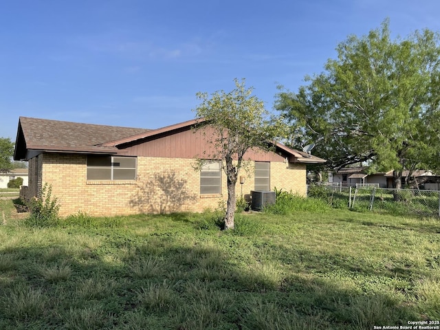 608 Leona St, Cotulla, TX 78014 - view of property exterior featuring brick siding, fence, roof with shingles, and central air condition unit