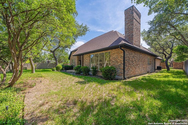17338 Fountain Mist, San Antonio, TX 78248 - view of home's exterior featuring a chimney, brick siding, central AC, and roof with shingles