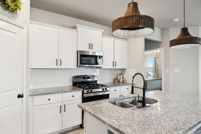 31575 Meander, Bulverde, TX 78163 - kitchen with appliances with stainless steel finishes, a sink, backsplash, white cabinetry, and an island with sink