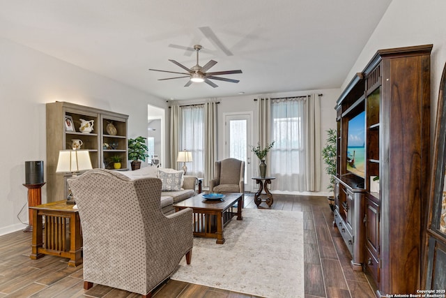 living area with dark wood-style floors, ceiling fan, and baseboards