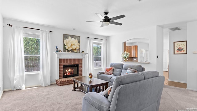8818 Ash Mdw, Universal City, TX 78148 - living room featuring light colored carpet, ceiling fan, a fireplace, baseboards, and arched walkways