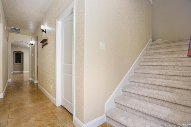 12302 Calvert, Helotes, TX 78023 - staircase featuring arched walkways, a textured ceiling, tile patterned flooring, and baseboards